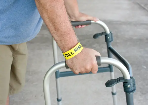 A patient with their hip flexed after surgery using a walker 